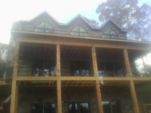 Dormers and porch framing on a large log home under construction — Roof Coating work by our crew in Blue River