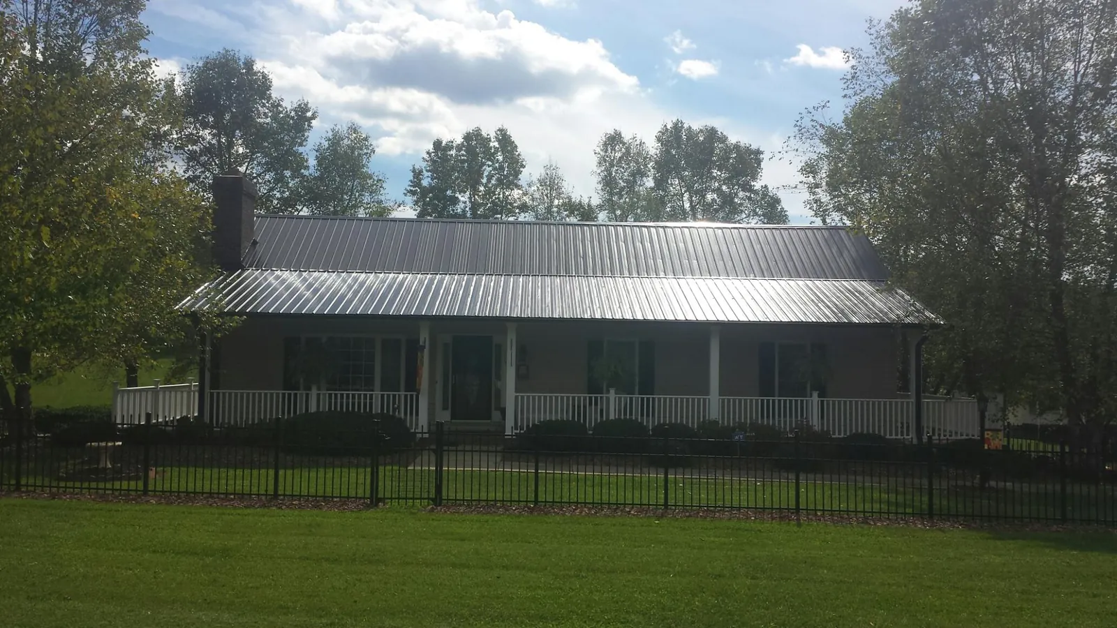 Gray metal roof on a brick ranch with a full width front porch — Gutter Guard Installation work by our crew in Blue River